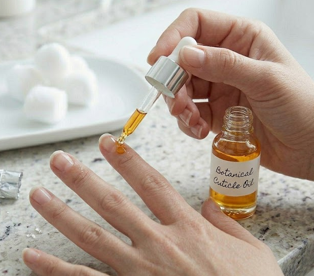 Applying nourishing cuticle oil to the nail and skin, massaging it in to restore hydration after gel removal.