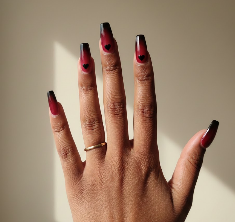 Nails fade from black to scarlet red with heart patterns, romantic and striking