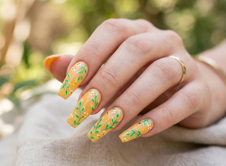 Honey Locust – Coffin shaped nails: Warm yellow-orange base, bright green branch-style leaves, tiny white dots, cheerful nails.
