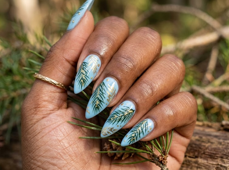 Pine Needles – Stiletto shaped nails: Sky blue base, dark green pine needle leaves, gold dots, thin patterns, cool summer nails.