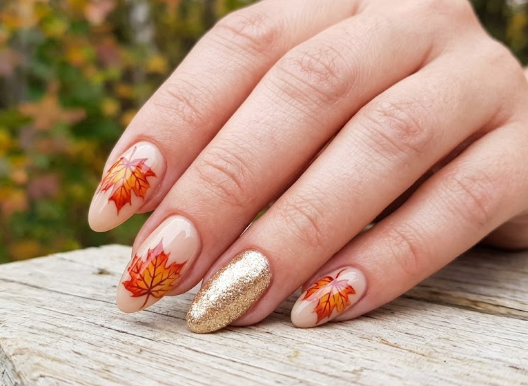 Sugar Maple – Almond shaped nails: Beige base, red-orange maple leafs, gold shimmer accent, warm autumn nails.