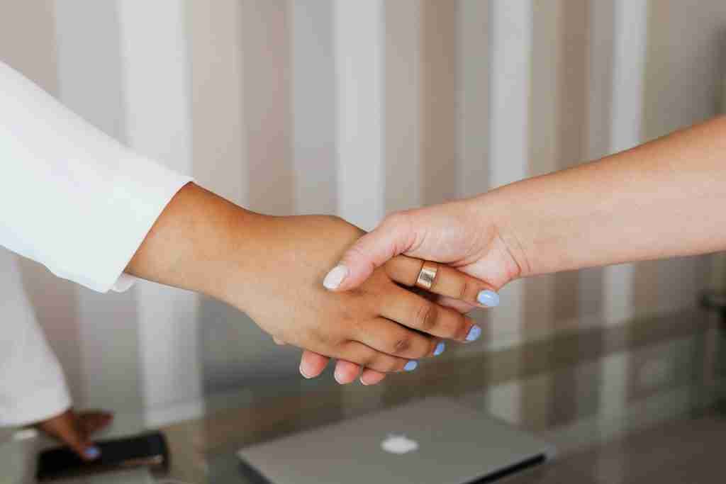 a young woman shaking hands with another young woman