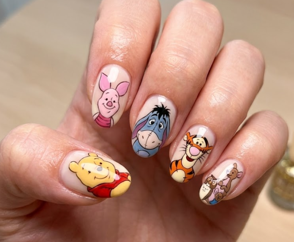 This nail design shows Pooh with all his friends (Piglet, Tigger, Eeyore, Rabbit, and Owl) on different nails, creating a complete cartoon world and a colorful story-like feel.