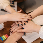 Team members in office meeting with visible clean, well-groomed nails, professional and modern workspace.