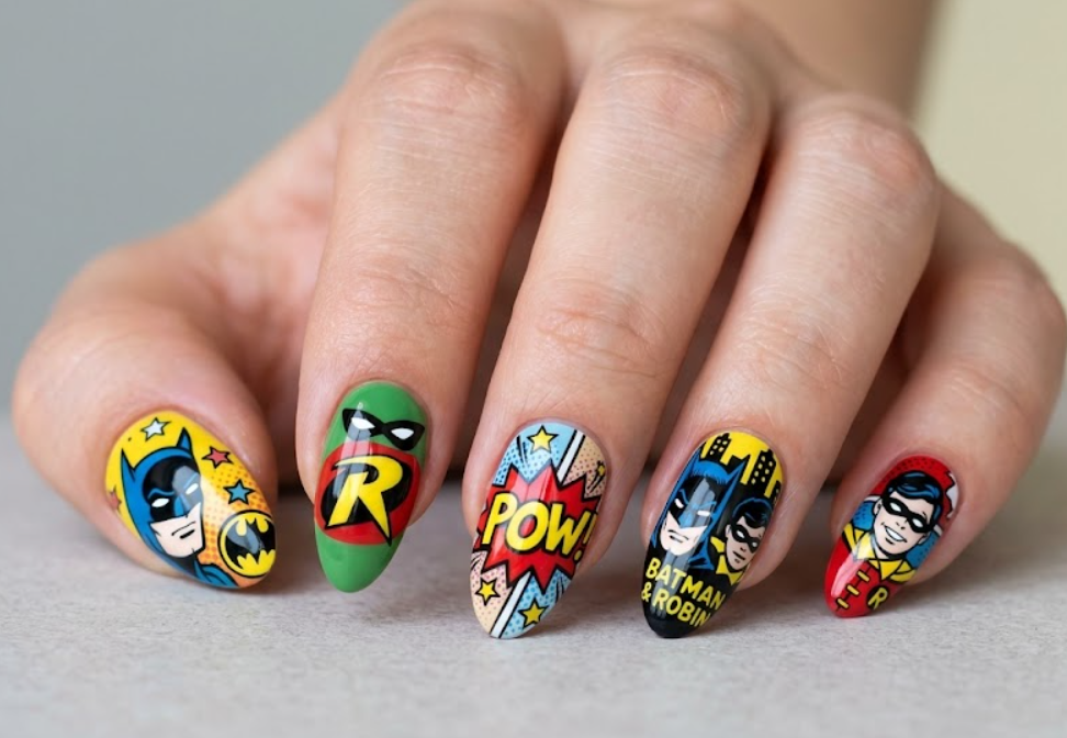 Full hand Batman and Robin comic-style colorful nails with red green and yellow details on a simple background