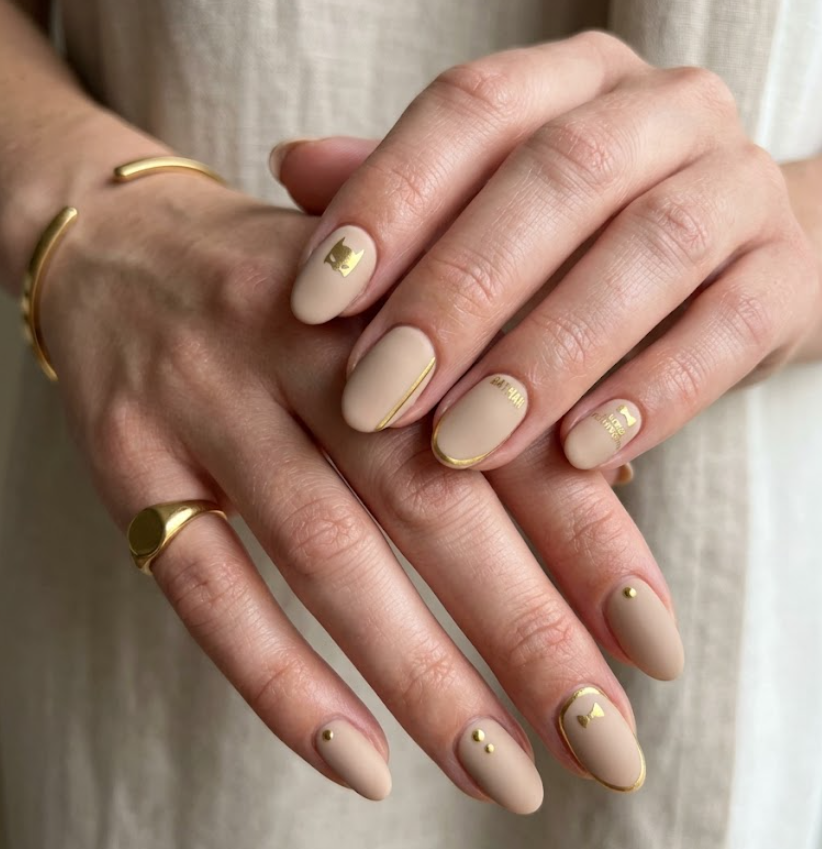Full hand Batman Alfred Pennyworth luxury neutral matte nails with gold accents on a simple background