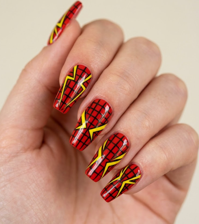 A high-contrast macro shot of Spider-Woman inspired nails with a bold red base, sharp yellow graphic accents, and geometric black web grids.