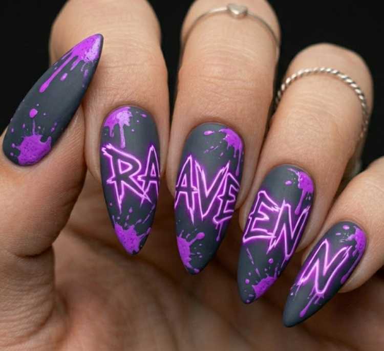 Arrowhead shaped matte charcoal nails with bright neon purple paint drips and the name Raven tagged across the nails in a street graffiti font.