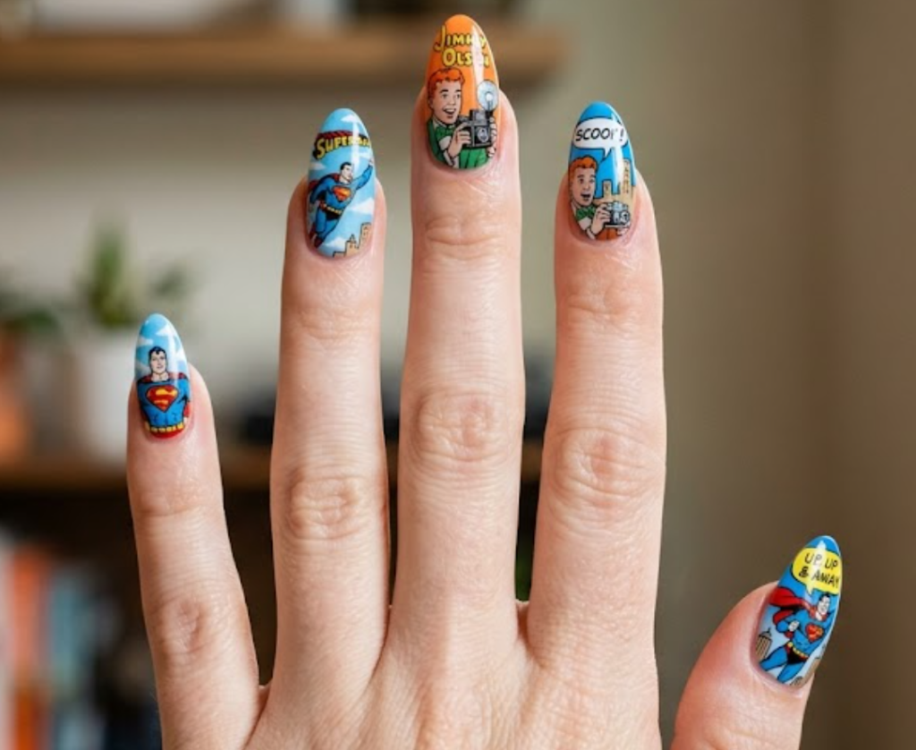 A woman’s hand with bright comic nails featuring Jimmy Olsen holding a camera and Superman flying behind him.