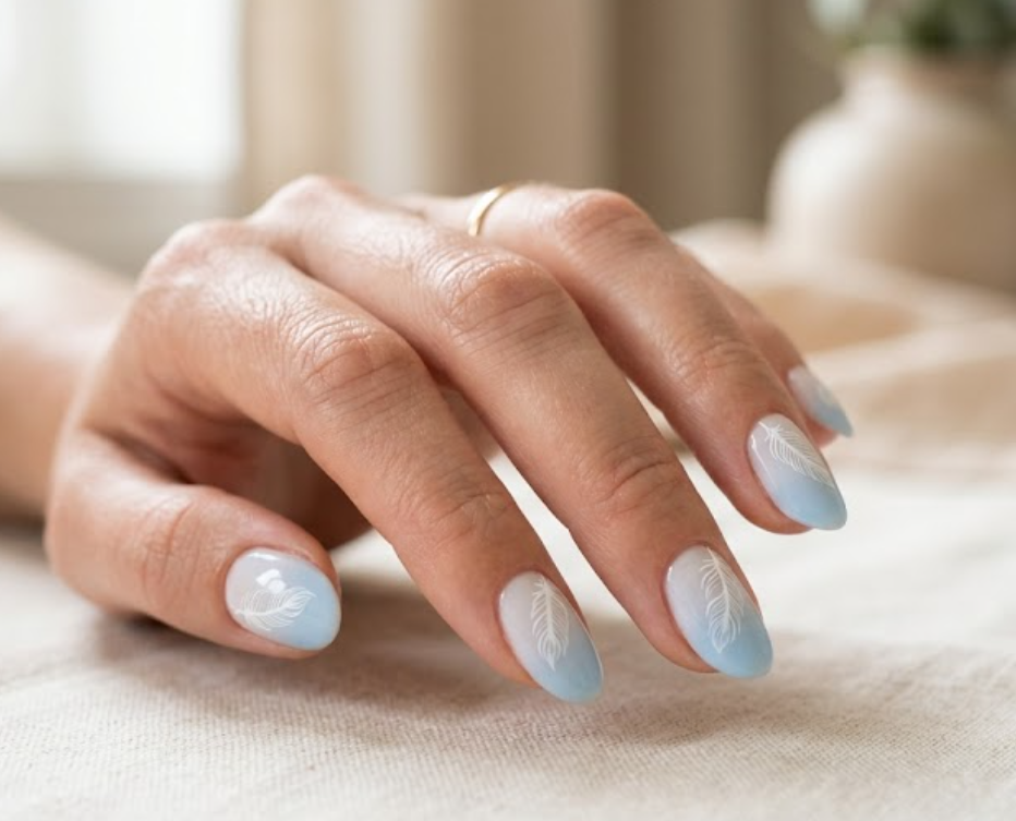 In this picture, oval nails show minimalist goose feather nail art on a soft blue gradient base.