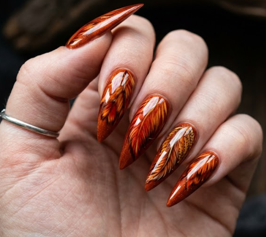 In this picture, stiletto nails feature fiery rooster feather nail art with glossy red-orange details.
