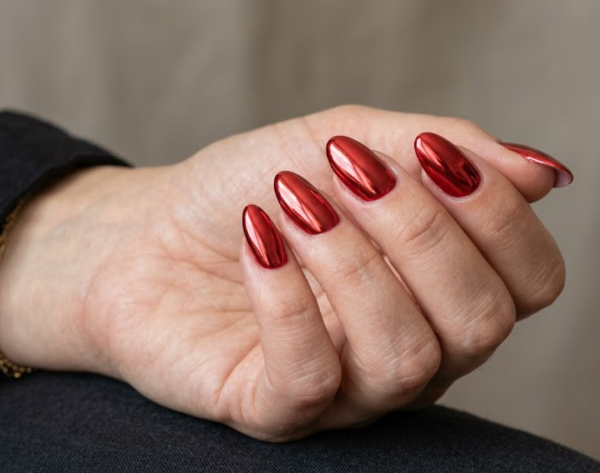 This image shows reflective red chrome nails with a modern metallic finish on a female hand.