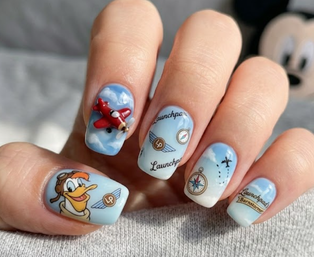 Launchpad McQuack inspired nail design with airplanes, clouds, pilot badges, and adventure-themed artwork.