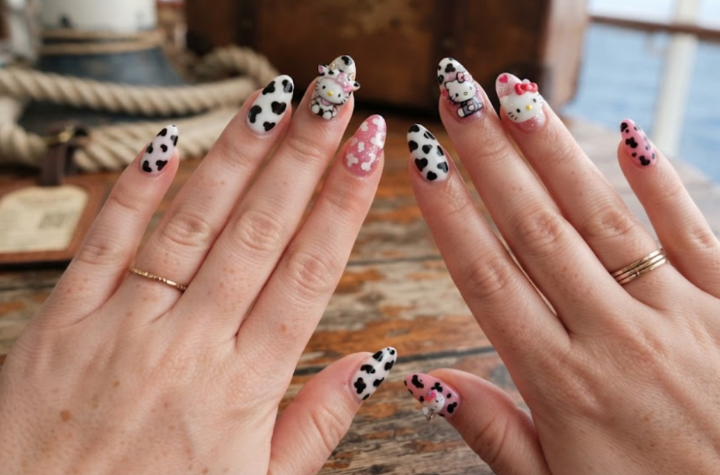 Quirky Hello Kitty nail design featuring fun cow print pattern accents.