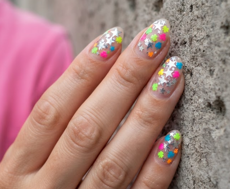 In this image, a playful 4-Leaf Clover Nail mixes silver metallic stars and neon clover designs with a hot pink shirt.
