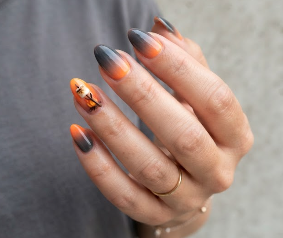 in this image real hands display a campfire embers ombre camp nail design. camp inspired nail design