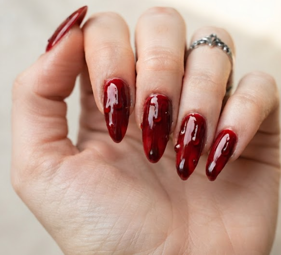 In this photo, glossy blood red nails feature realistic dripping blood details for a bold and spooky manicure.