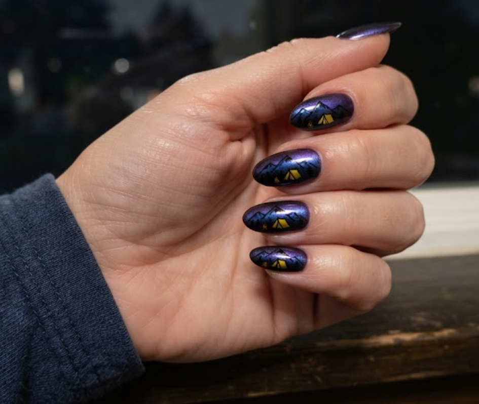 in this image real hands showcase northern lights chrome camp nail art. camp inspired nail design