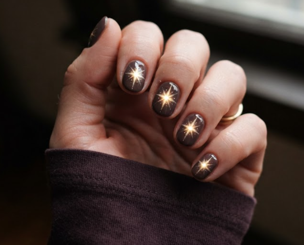 In this image, full hands with short round nails feature a glowing starburst effect over velvet taupe against a moody window background.
