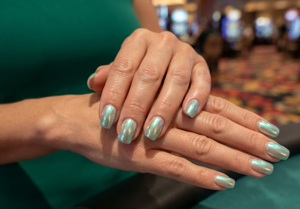 In this image, cruise wedding nails showcase short squoval full mermaid chrome nails with blue-green reflections, worn by hands in an emerald dress.