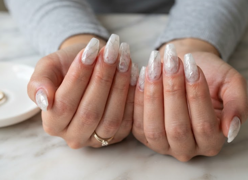 imageIn this image, cruise wedding nails feature short coffin clear quartz nails with fine silver veins, worn by hands in a silver grey shirt.