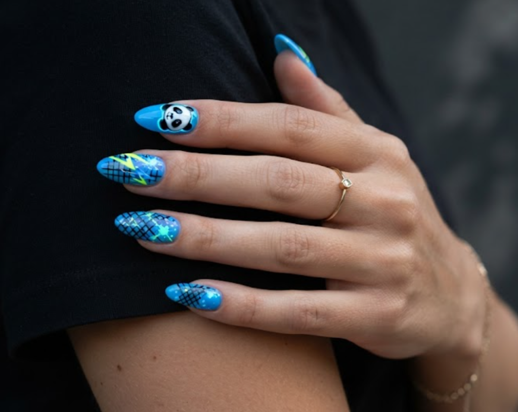 In this image, medium-length almond-shaped nails with a vibrant neon electric blue base are shown. The design features a black-and-white panda face with neon blue outlines. Others have neon geometric lightning bolts, black grid lines, and glowing splash marks. The hand wears a black shirt.