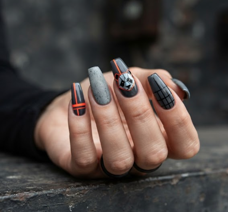 In this image, coffin-shaped nails with a dark charcoal grey base are highlighted. The design features a modern minimalist geometric panda. Others display neon orange accent stripes, concrete-effect textures, and urban grid lines. The hand wears a black long-sleeved shirt.