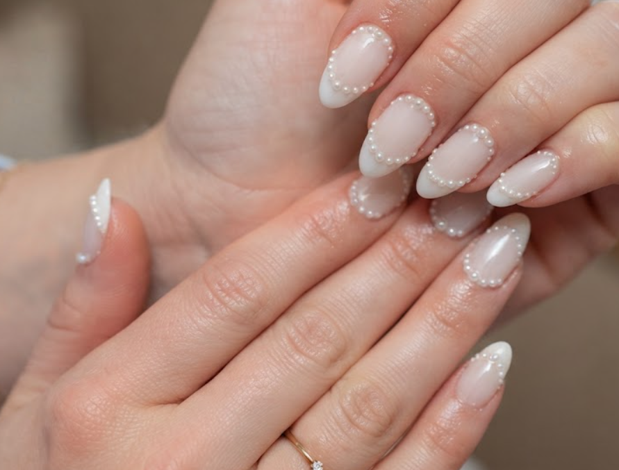 Milky white almond nails with elegant French tips and pearl accents, perfect for cruise honeymoon.
