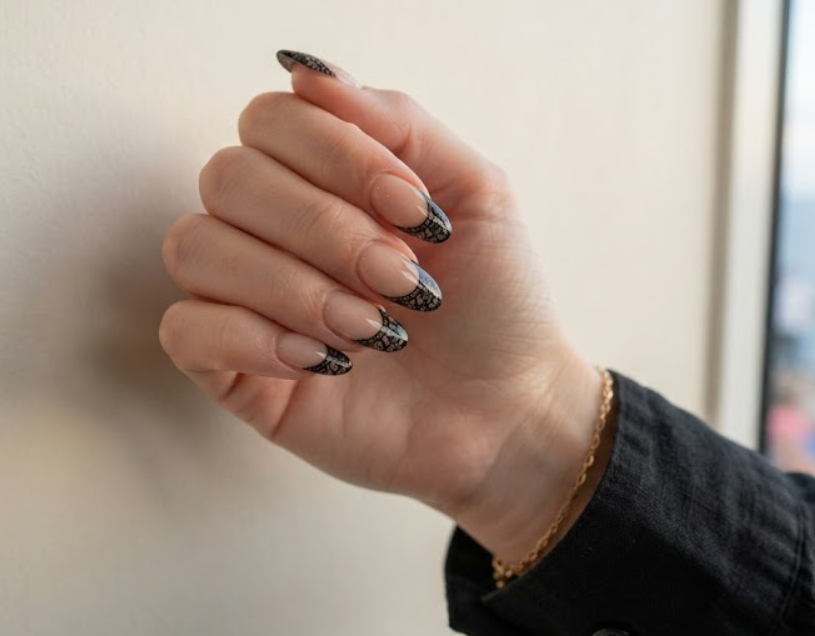 Glossy nude nails featuring black lace French tip design.