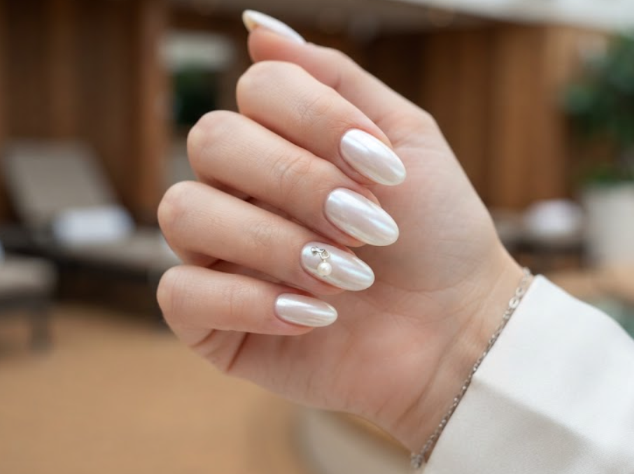 White pearlescent glazed donut honeymoon nails decorated with a dangling pearl charm.