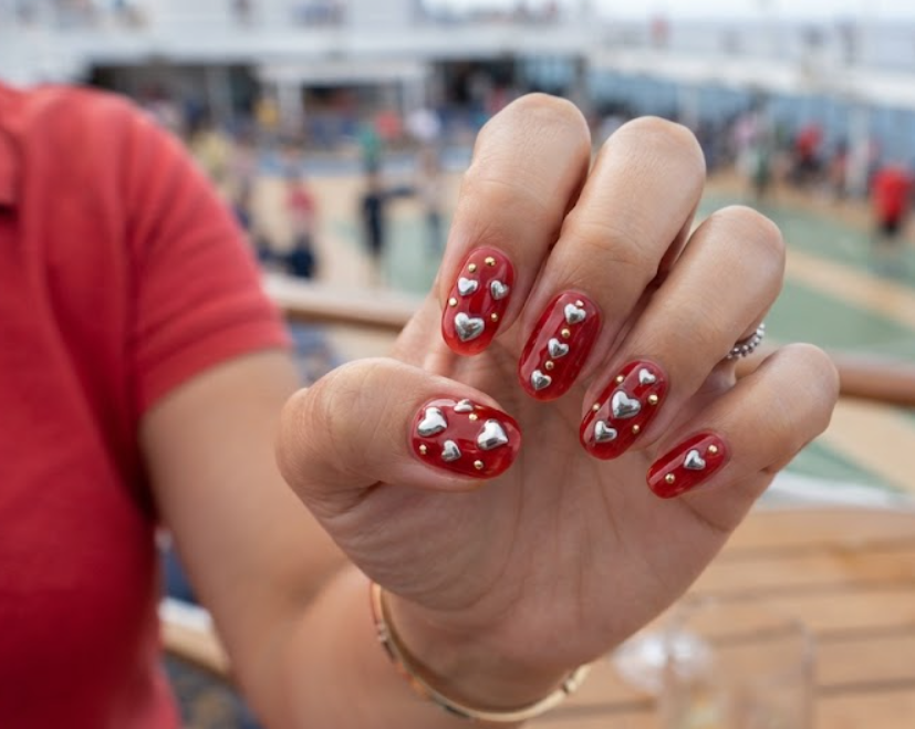Translucent red jelly honeymoon nails featuring polished 3D silver chrome hearts and gold studs.