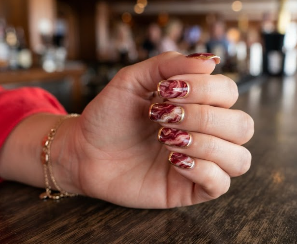 Cherry red marble honeymoon nails finished with a sharp gold chrome outline.