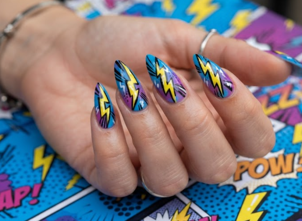 In this image, blue and purple comic nails feature bright yellow lightning bolts and action lines.