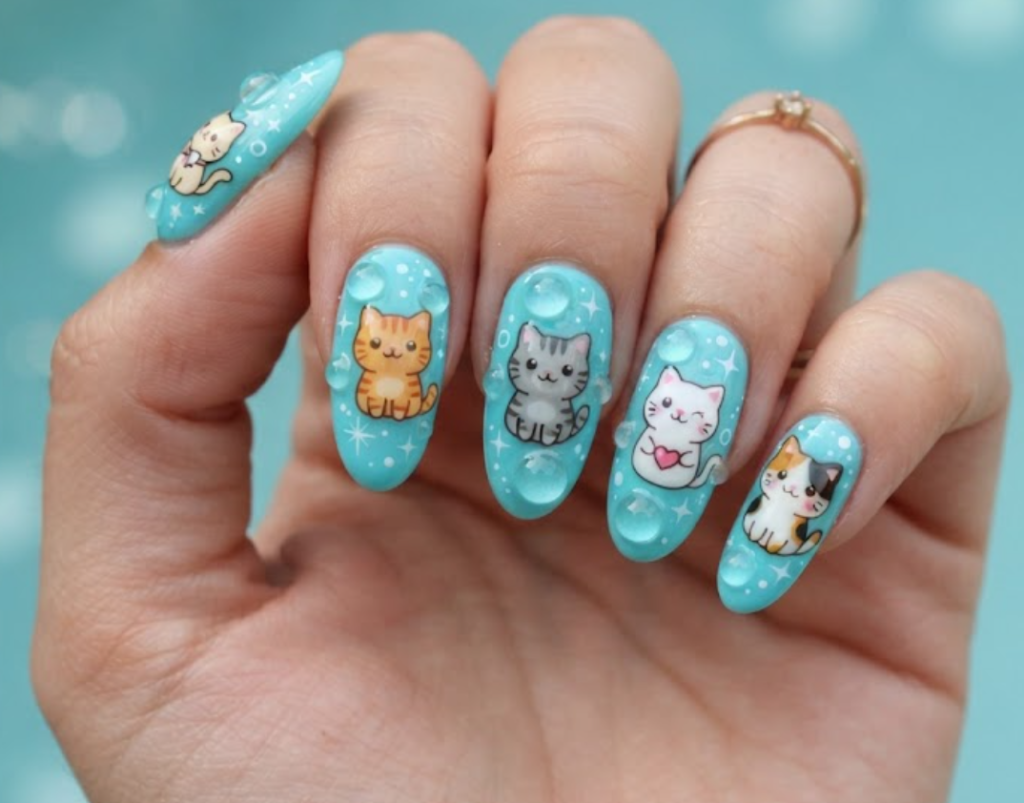 In this image, aqua blue nails with cute cartoon cats inside bubbles