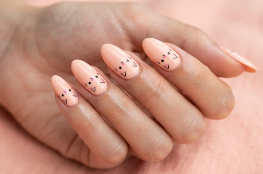 In this image, baby peach nails with minimalist cartoon cat faces