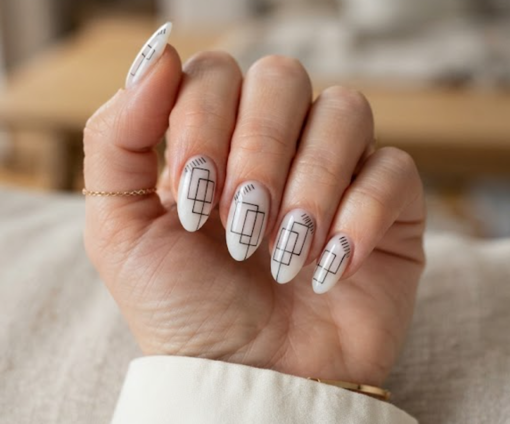 In this image, a woman's full hand displays milky white nails with overlapping black rectangle boxes and micro-ticks, wearing an off-white shirt.