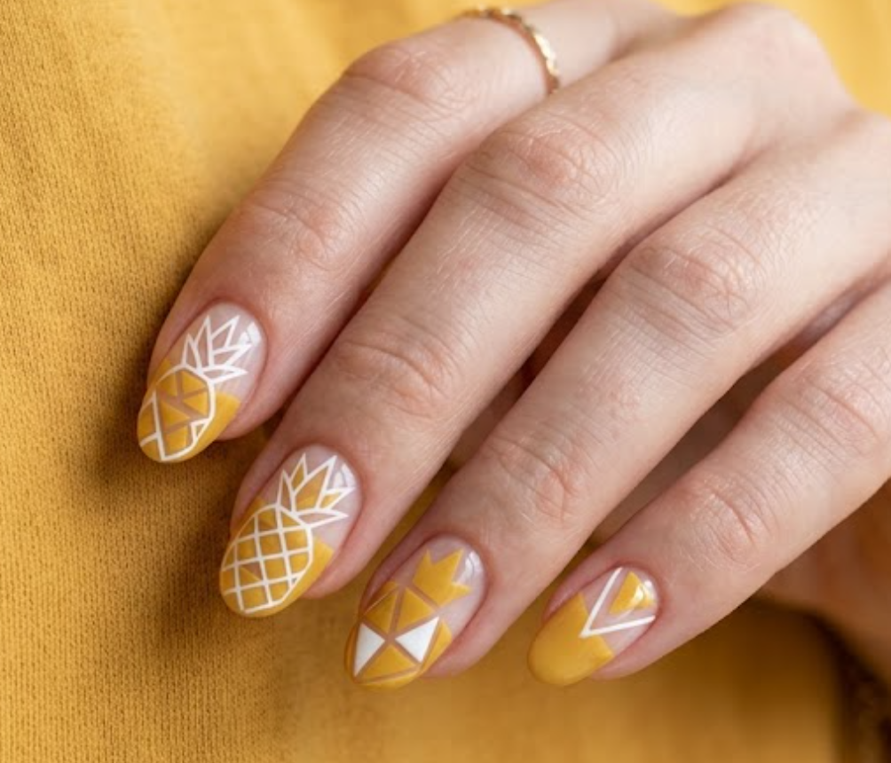 in this image, a hand in a mustard shirt displays negative space geometric shapes with a pineapple.