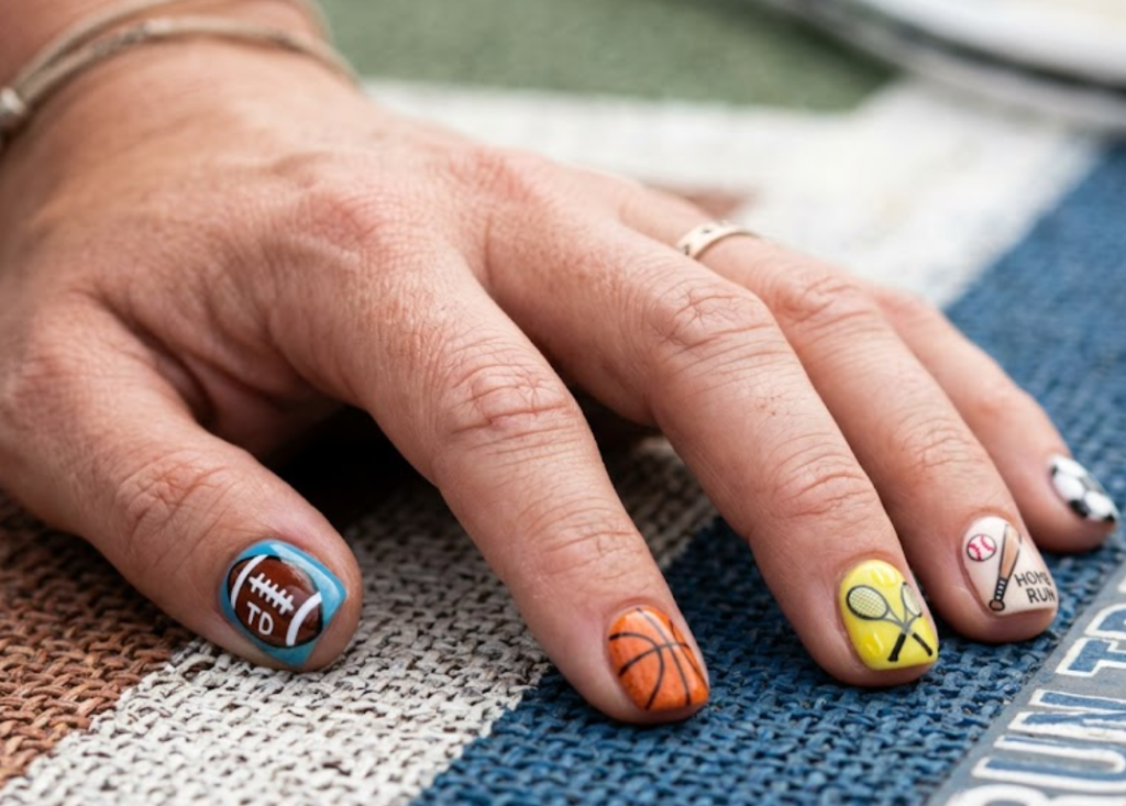 In this image, mixed sports nails featuring soccer balls, basketballs, tennis rackets, baseball bats, and sports equipment.